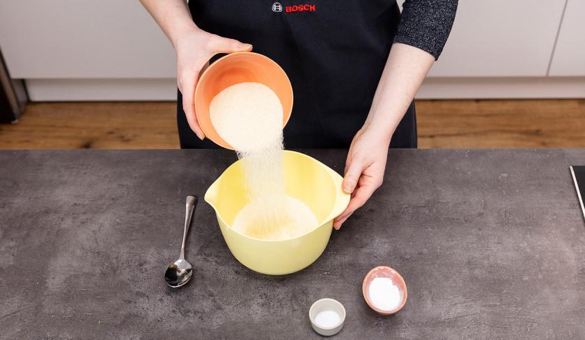 Grieß wird zum Mehl für den Grießkuchen in eine Rührschüssel gegeben.