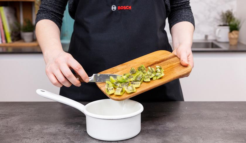 Für das Kiwikompott vom Grießkuchen werden Kiwiwürfel in einen Topf gegeben.