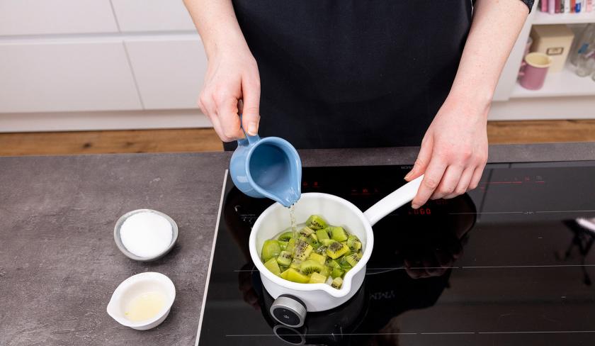Zu den Kiwiwürfel im Topf wird Wasser gegeben.