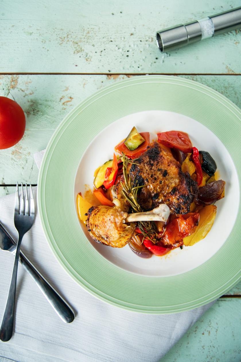 Hähnchenschenkel aus dem Ofen auf Gemüse auf einem Teller.