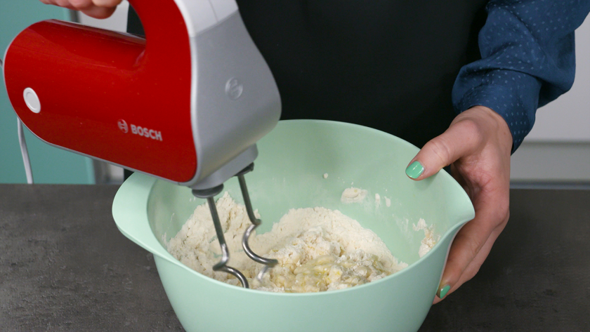 Der Teig für die Hefeblume mit rotem Pesto wird mit einem Handrührgerät geknetet.