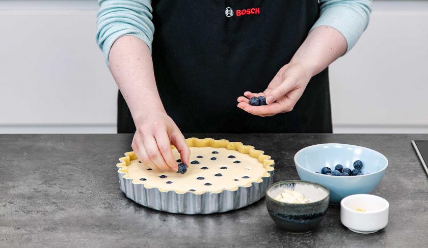 Der Heidelbeerkuchen mit Schmand wird mit Blaubeeren belegt.