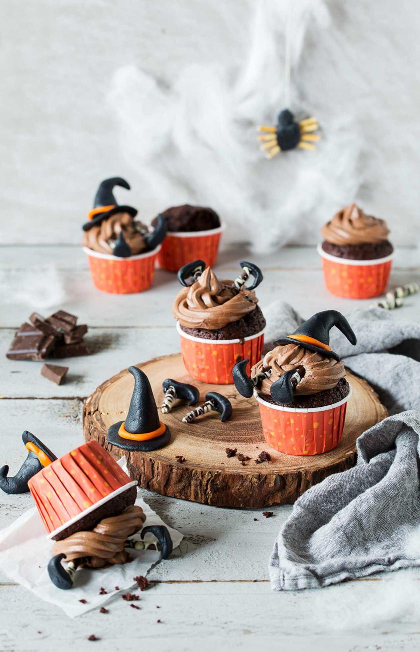 Mehrere Hexen-Cupcakes für Halloween auf einem Tisch angerichtet.