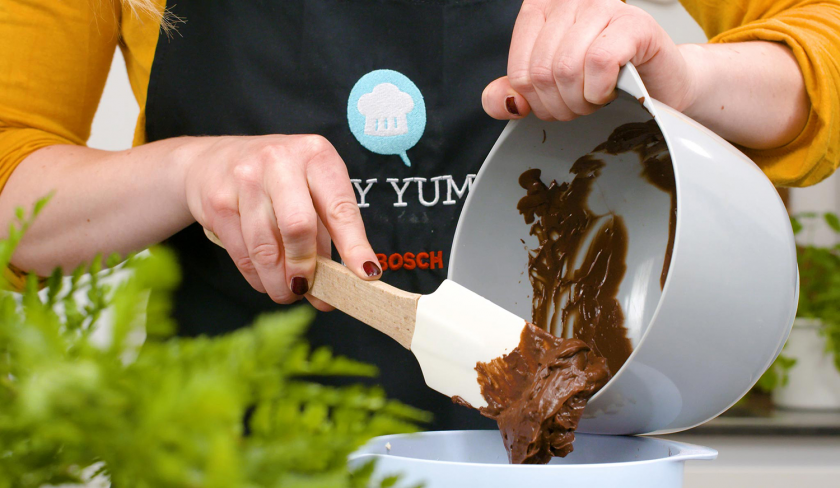 Schokoladen-Ganache wird zum Frosting für die Hexen-Cupcakes für Halloween gegeben.