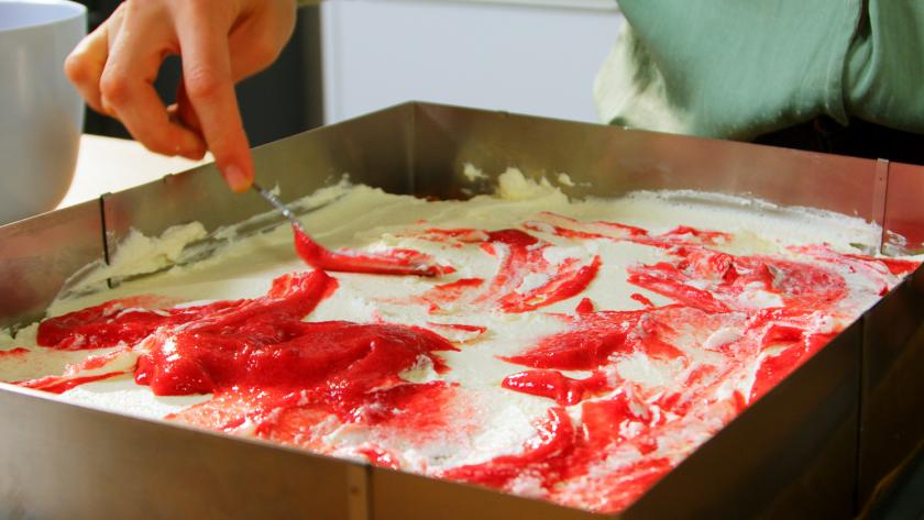 Himbeerpüree wird auf der Creme für die Himbeer-Quark-Torte verteilt.