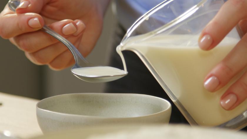 Milch wird auf einen Esslöffel gegossen.