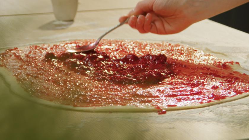 Himbeermarmelade wird auf dem Teig für die Himbeer-Schnecken verteilt.