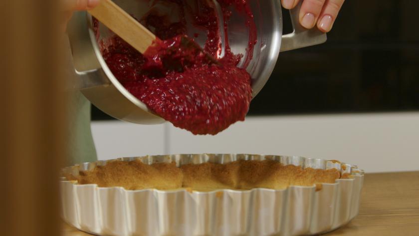 Himbeermasse wird auf den Boden der Himbeertarte mit weißer Schokolade gegeben.