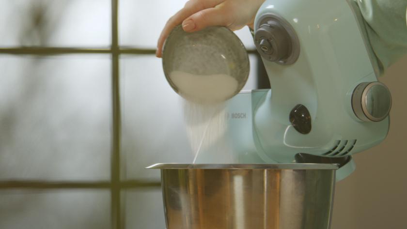 Zucker wird in die Rührschüssel einer Küchenmaschine gegeben.