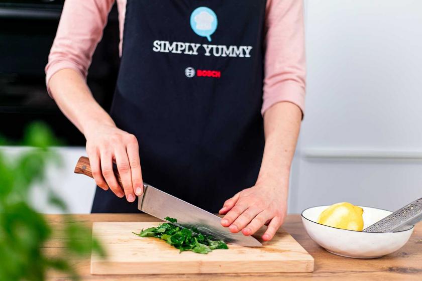 Petersilie wird auf einem Holzbrett gehackt.