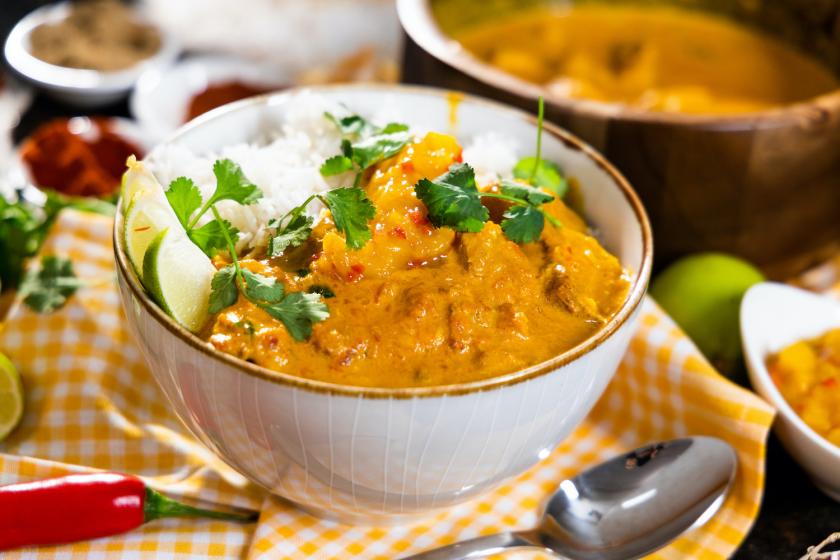 Indisches Butter Chicken mit Reis und Koriander in einer Schale angerichtet.