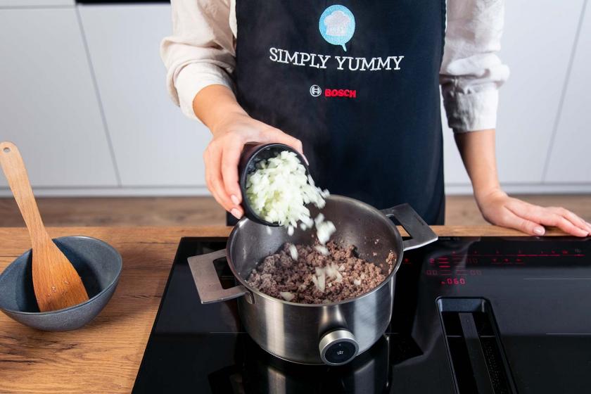Zwiebel wird zu Hackfleisch in einen Topf gegeben.