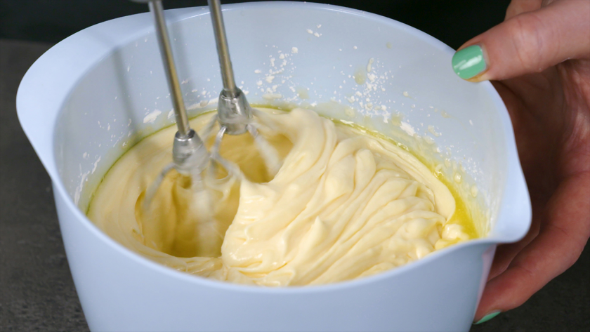 Die Füllung für die Käsekuchenmuffins mit Streuseln wird in einer Schüssel mit einem Handmixer verrührt.