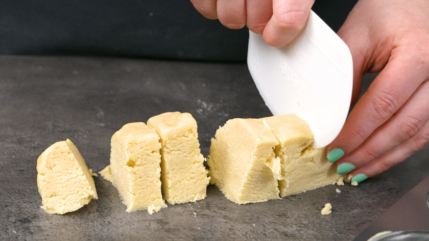 Der Mürbeteig wird für den Boden der Käsekuchenmuffins mit Streuseln portioniert.