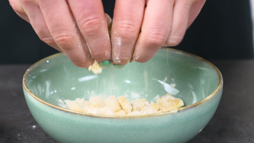 Teig wird mit Mehl zerkrümelt für das Topping der Käsekuchenmuffins mit Streuseln.