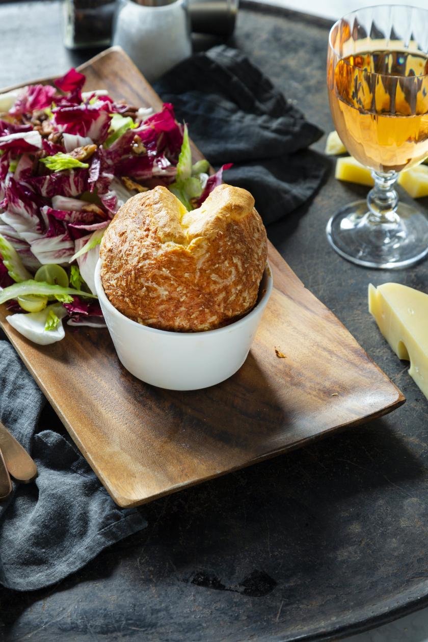 Käsesoufflé auf einem Brett mit einem Traubensalat.