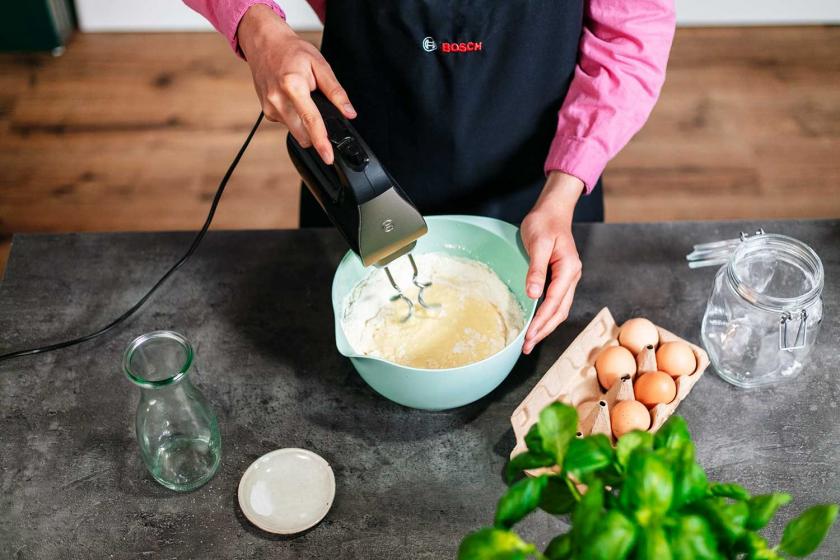 Der Teig für Käsespätzle wird in einer Rührschüssel mit einem Handmixer verquirlt.