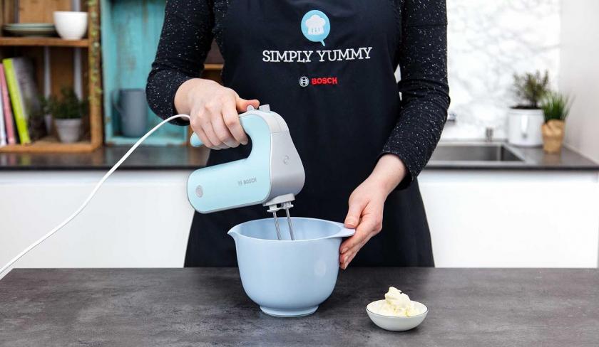 Für den Kaffeekuchen mit Walnusskrokant wird das Frischkäsefrosting mit einem Handmixer in einer Schüssel gerührt.