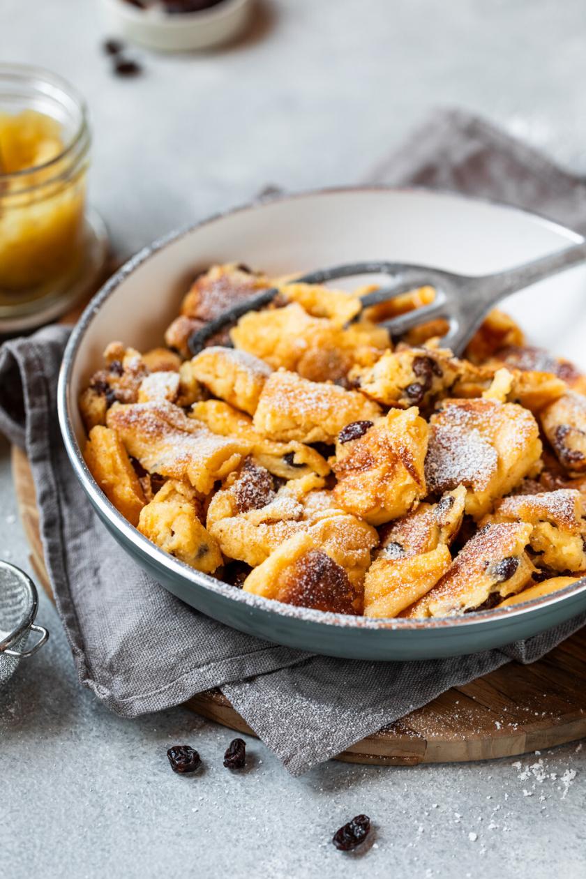 Kaiserschmarrn in einer Pfanne, daneben ein Glas selbstgemachtes Apfelmus