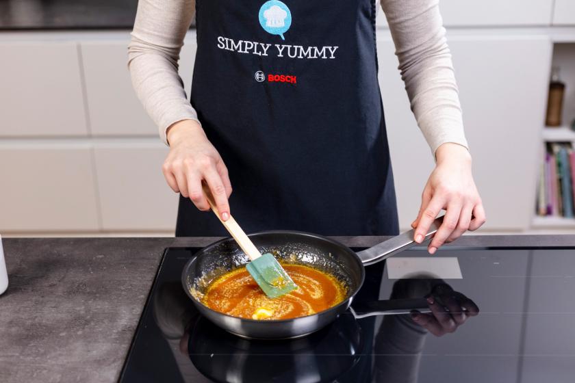 Butter wird in das Karamell in der Pfanne eingerührt.