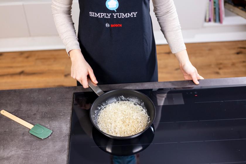 Zucker und Wasser köcheln in einer Pfanne.