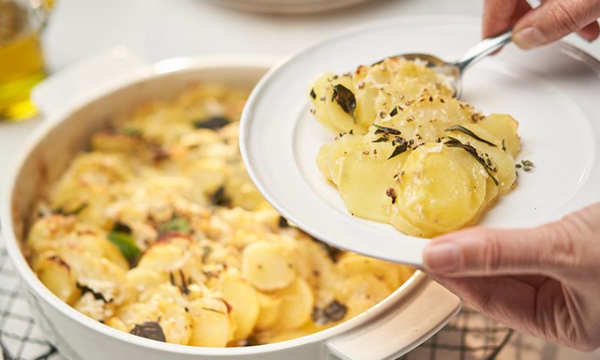 Kartoffelgratin mit Pecorino und Rosmarin wir aus Auflaufform auf Teller gegeben.