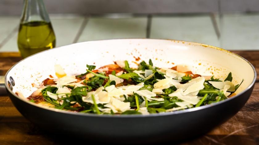 Kartoffelpizza mit Tomaten, Mozzarella und Rucola in der Pfanne gebacken