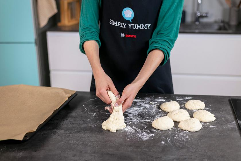 Der Teig für die Käsebrötchen wird auf einer Arbeitsfläche portioniert undgeformt.