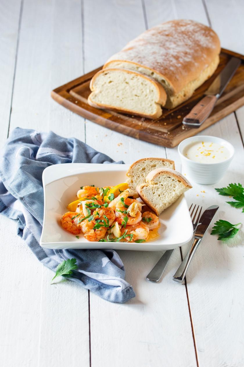 Knoblauchgarnelen auf Teller mit zwei Scheiben Brot.