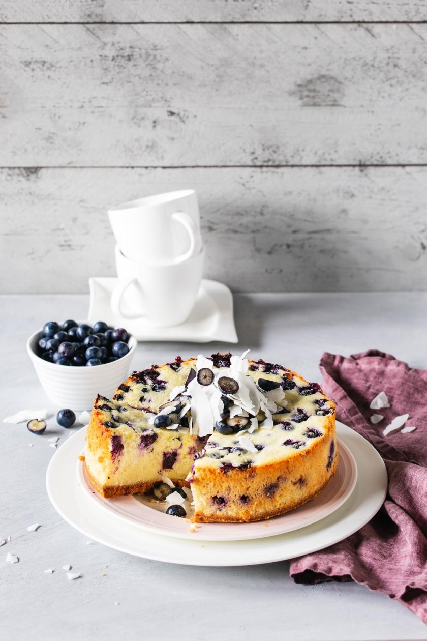 Angeschnittener Kokos-Käsekuchen mit Heidelbeeren.