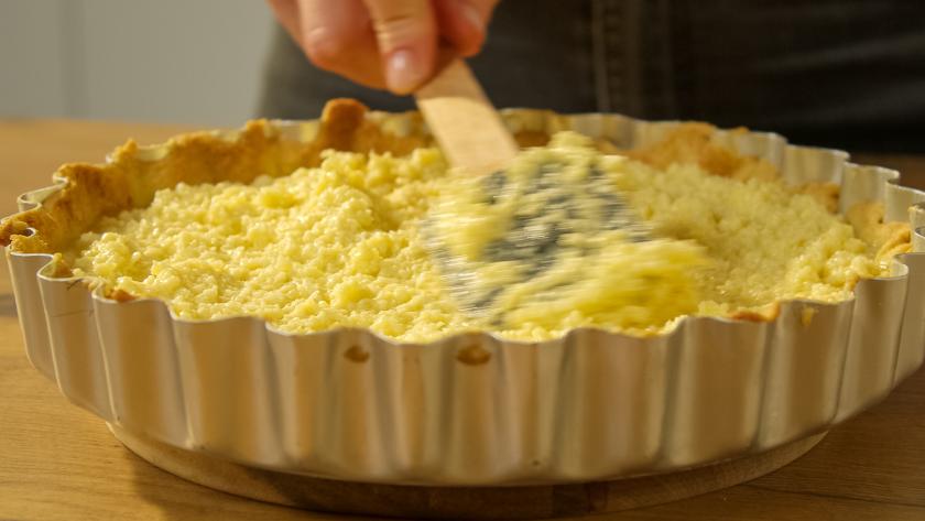 Kokosfüllung für Kokos-Pie mit Mracuja Curd wird auf dem Boden verteilt.