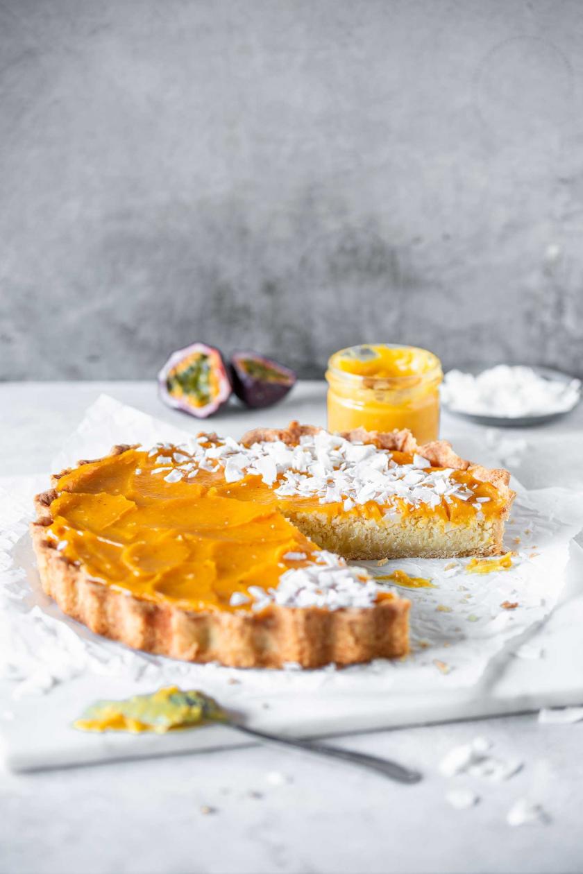 Kokos-Pie mit Maracuja Curd angeschnitten auf einem Brett.