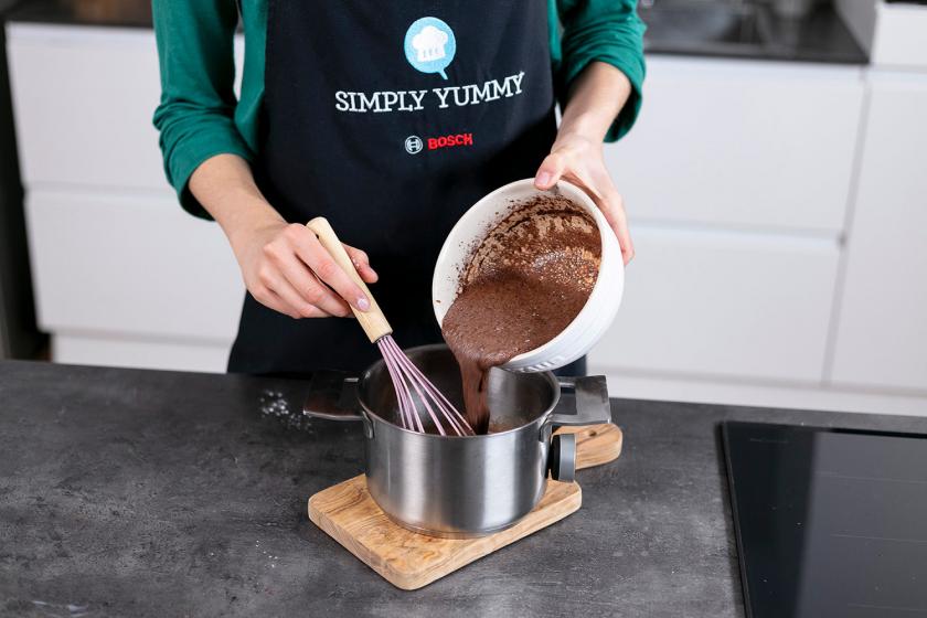 Puddingmasse wird in einen Topf mit heißer Milch eingerührt.