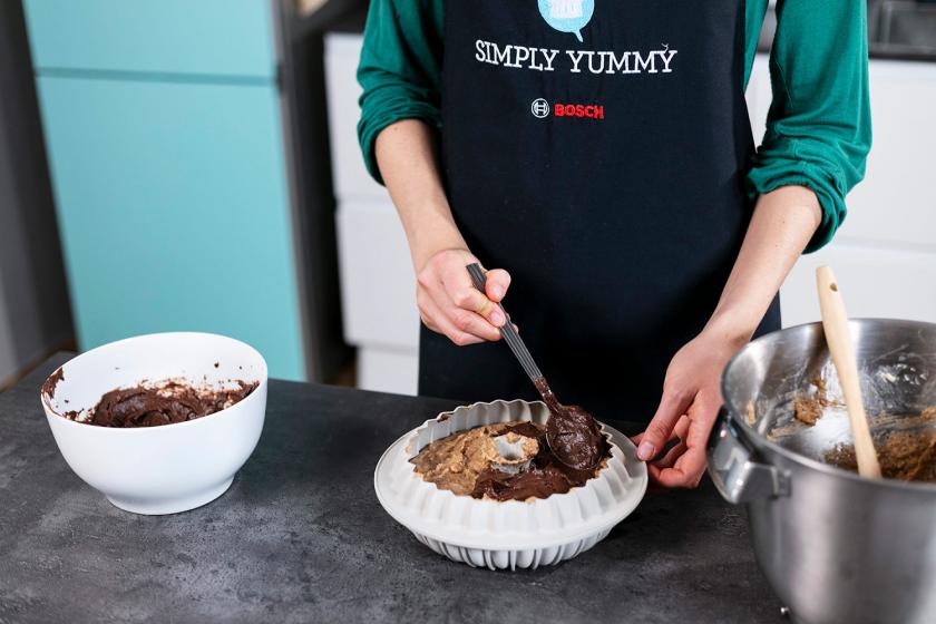 Pudding wird auf dem Teig in der Gugelhupfform verteilt.