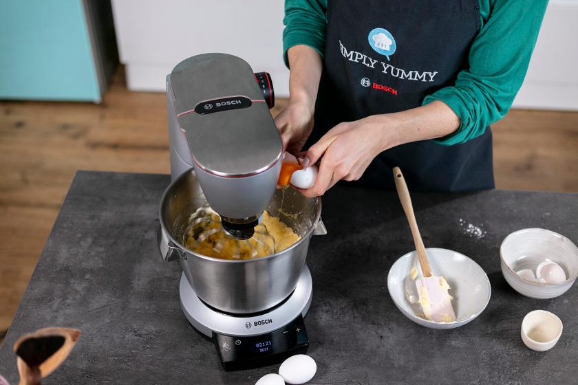 Ei wird zum Teig in der Rührschüssel einer Küchenmaschine gegeben.