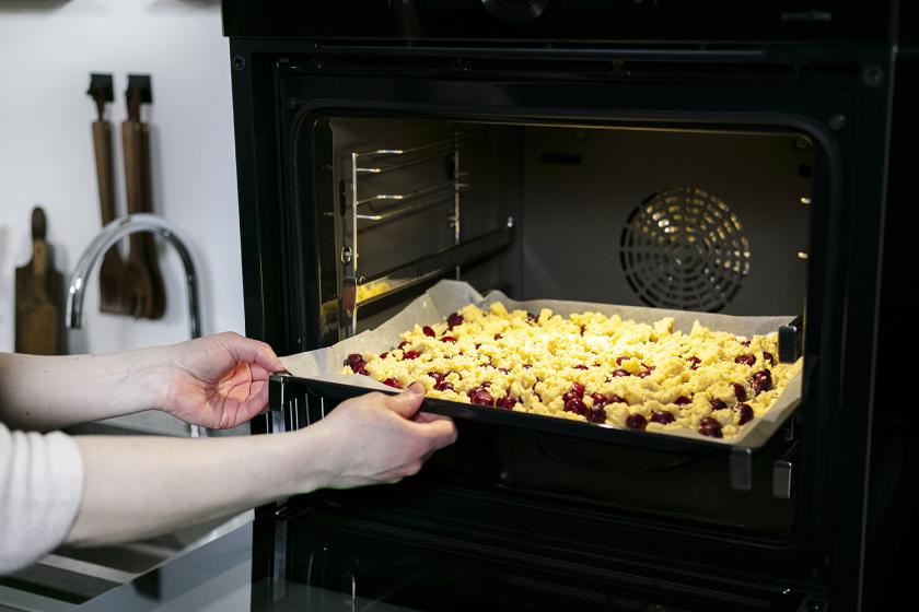 Der Kuchen mit Süßkirschen wird in den Ofen geschoben.