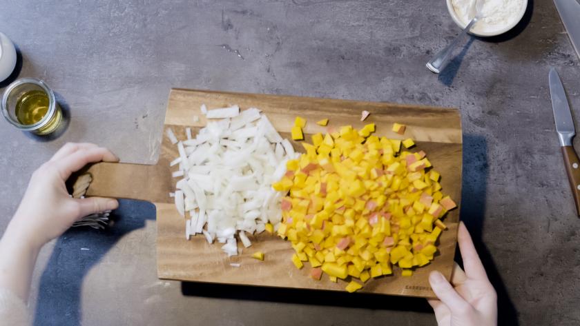Für die Füllung des Kürbisstrudels liegen gewürfelte Zwiebel und Kürbis auf einem Holzbrett.