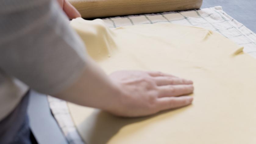 Der Strudelteig wird auf einem Küchenhandtuch ausgezogen.