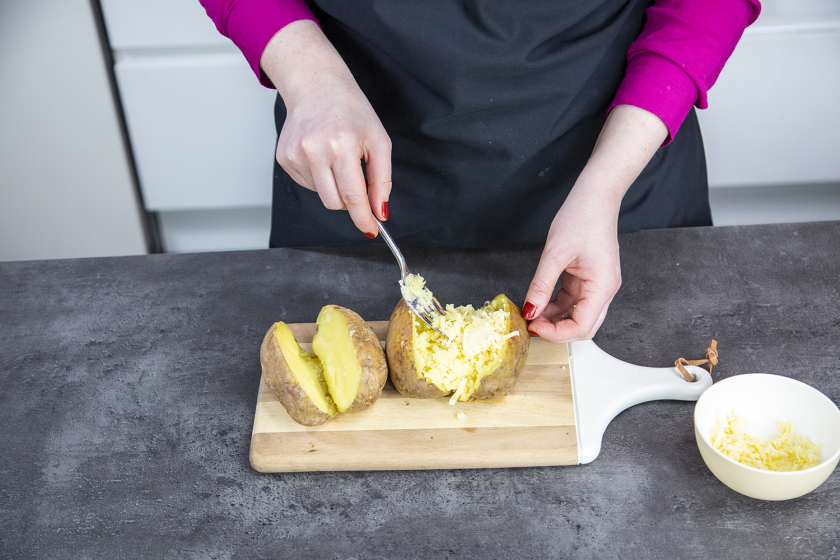 Das Kartoffelinnere der Kumpir wird mit einer Gabel gelockert und mit Käse und Salz vermengt.