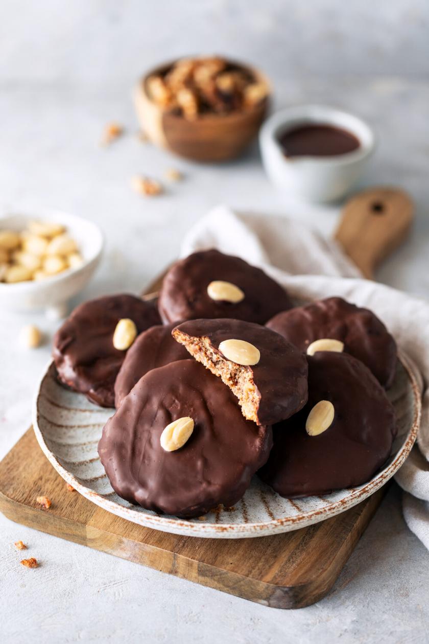 Zuckerfreie Lebkuchen gestapelt auf einem Teller, daneben Zutaten wie Mandeln auf einem Tisch