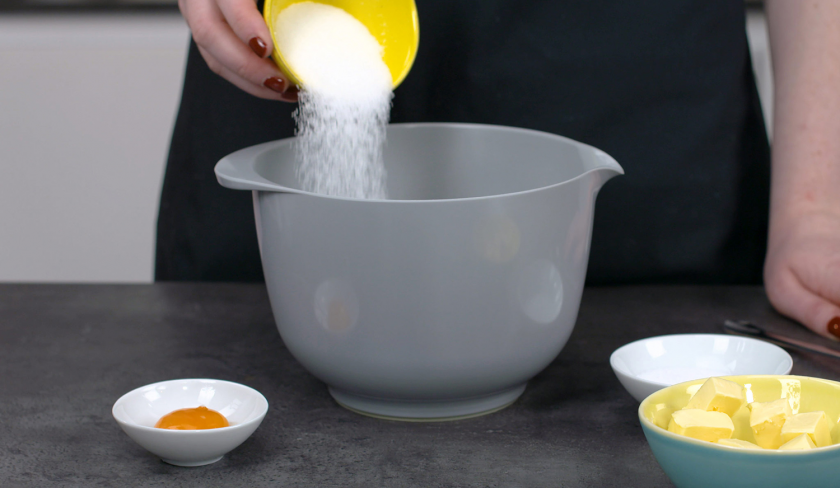 Für den Boden der Lemon Curd Tarte mit Balsamico-Kirschen wird Zucker in eine Schüssel gegeben.