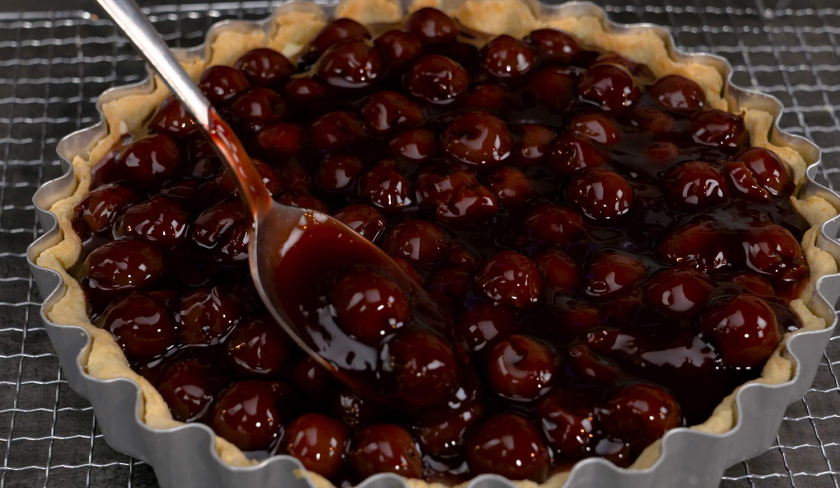 Die letzte Schicht der Lemon Curd Tarte mit Balsamico-Kirschen wird auf dem Kuchen verteilt.