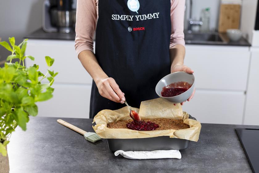 Auf den Linsenbraten wird Preiselbeermarmelade verteilt.