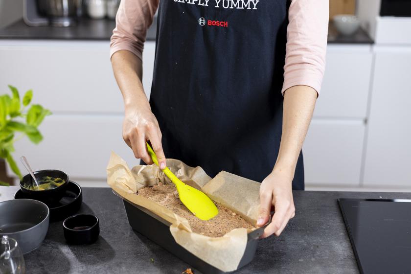Die Masse für den Linsenbraten wird in einer Kastenform mit einem Spatel glatt gestrichen.