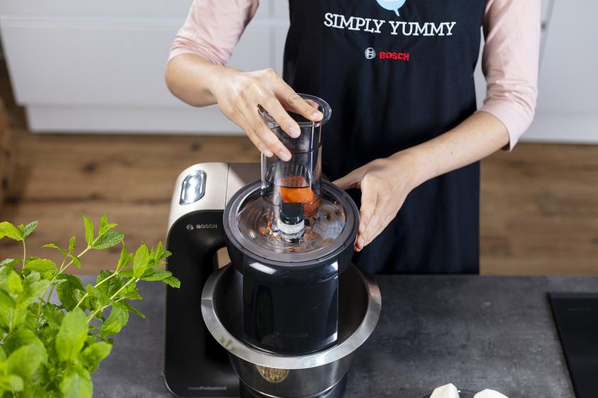 Möhre wird in einer Küchenmaschine gerieben.