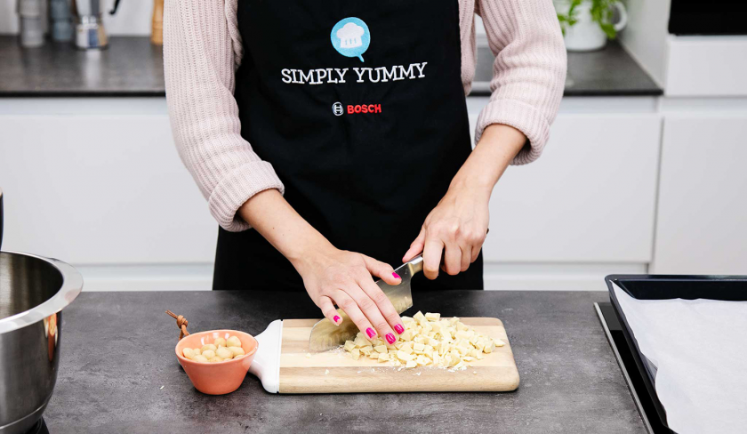 Für den Teig der Macadamia Cookies wird weiße Schokolade gehackt.