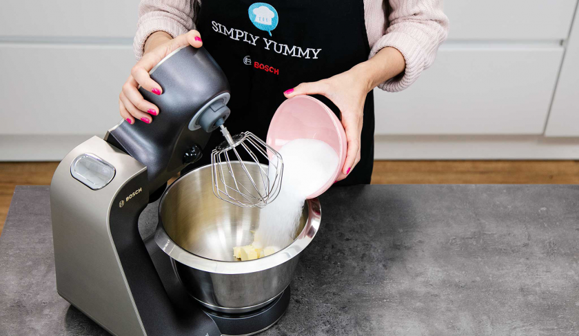 Für den teig der Macadamia Cookies wird Zucker in die Rührschüssel einer Küchenmaschine gegeben.