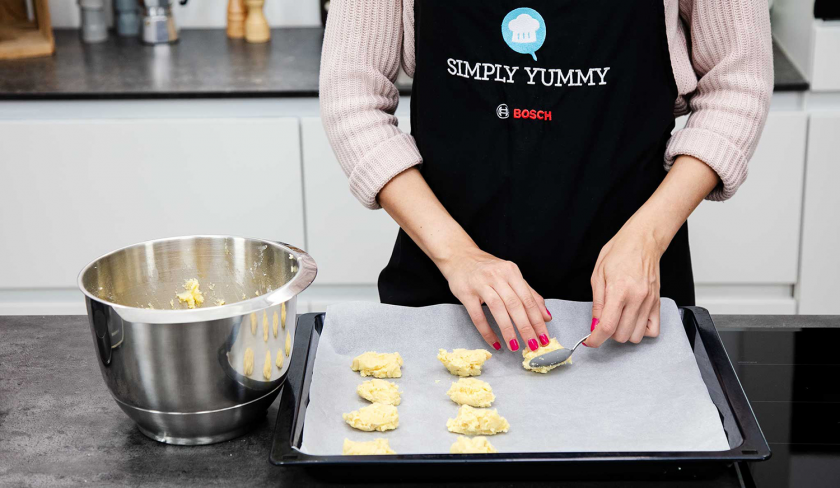 Mit einem Teelöffel wird der Teig fr die Macadamia Cookies auf einem Backblech verteilt.