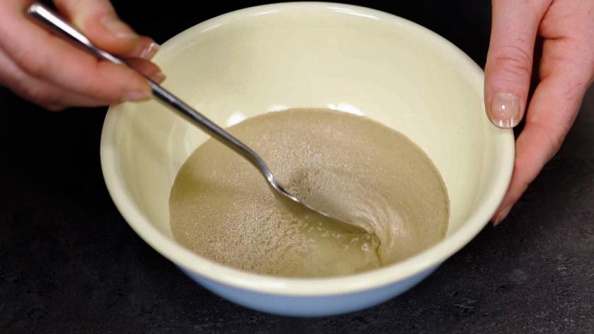 In einer Schüssel wird Hefe in Wasser eingerührt.