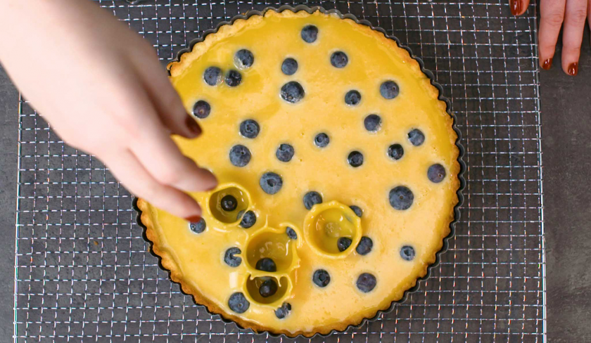 Blaubeeren werden auf die Füllung von der Maracuja-Tarte mit Blaubeeren gegeben.